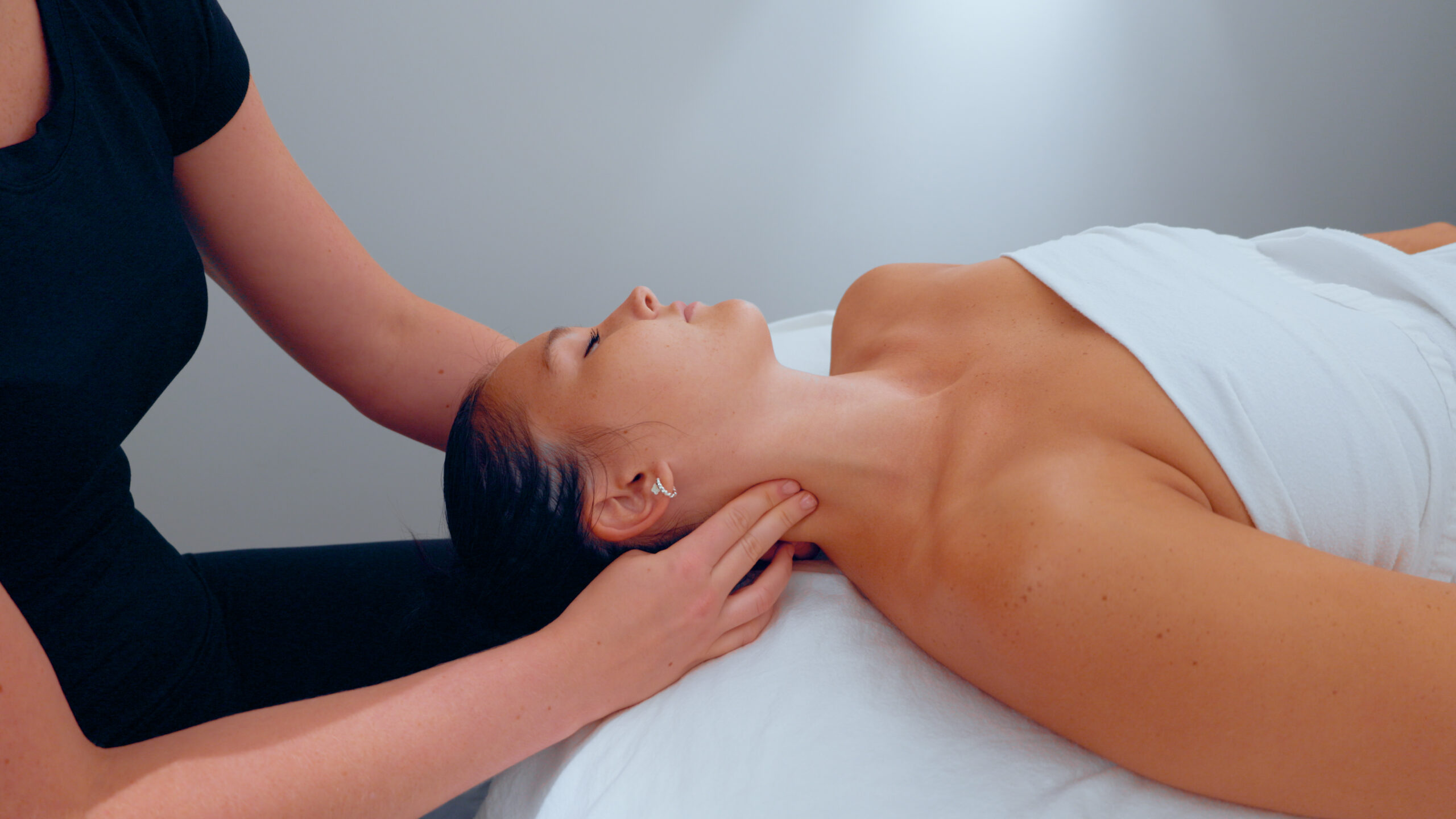Registered massage therapy treatment at Revamp Wellness with a therapist performing a neck massage to relieve tension and promote relaxation.