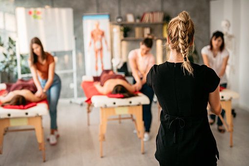 Women in massage school learning to be massage therapists